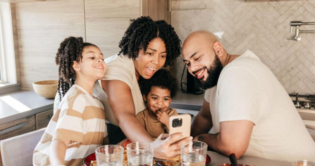 A smiling mother and father with their two kids sitting together, reflecting conscious mothering, emotional connection, and parenting with awareness